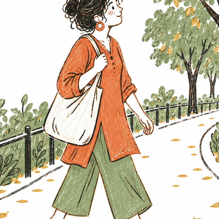 A person walking along a tree-lined path carrying a cloth bag.