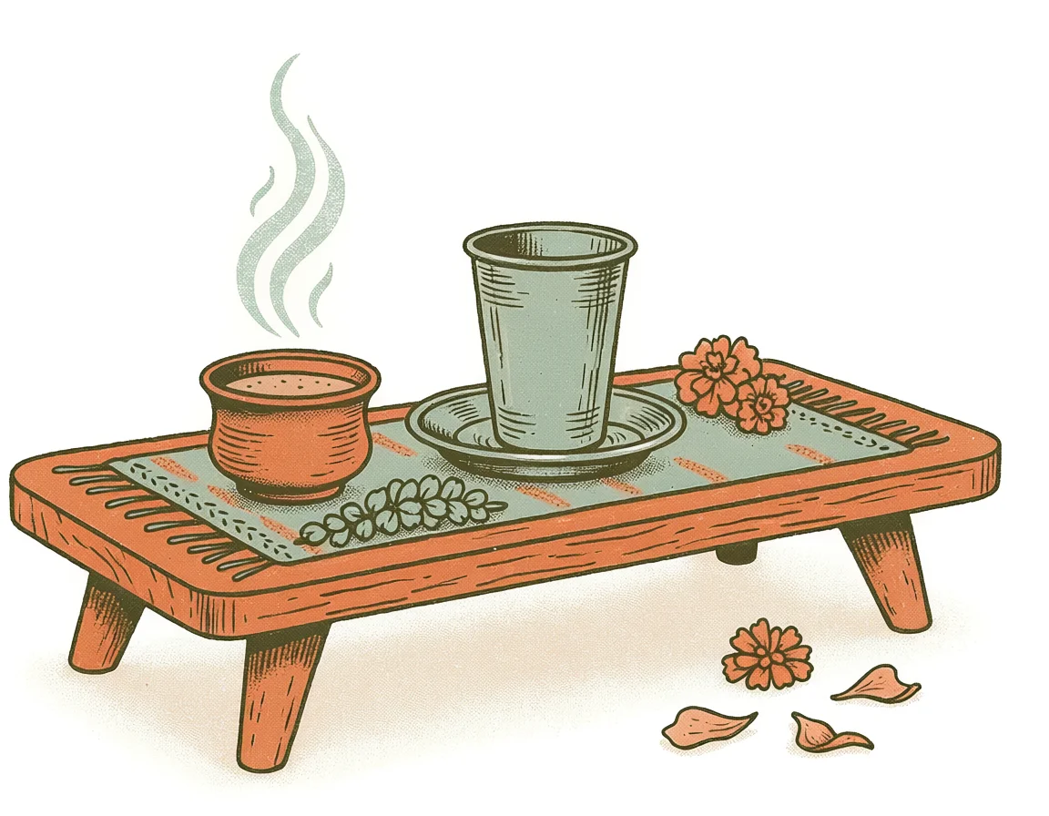 Hand-drawn low table with a woven runner, a clay kulhad of chai and a steel tumbler side by side, marigolds beside them